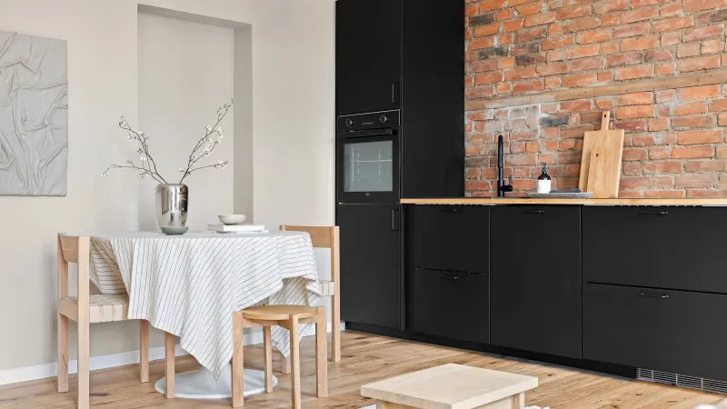 Apartment kitchenette with a small dining table, white tablecloth and black cabinets