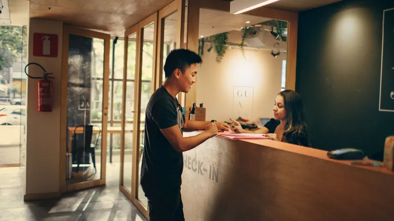 Guest standing at a small hotel reception desk talking to the receptionist