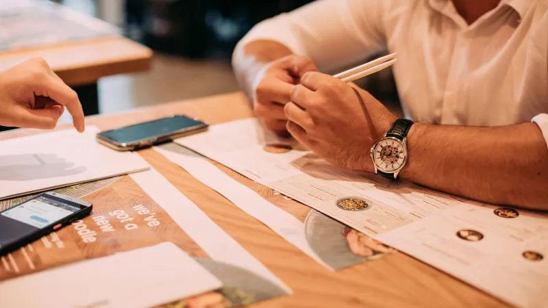 Printed menus and smartphones side by side on a wooden table