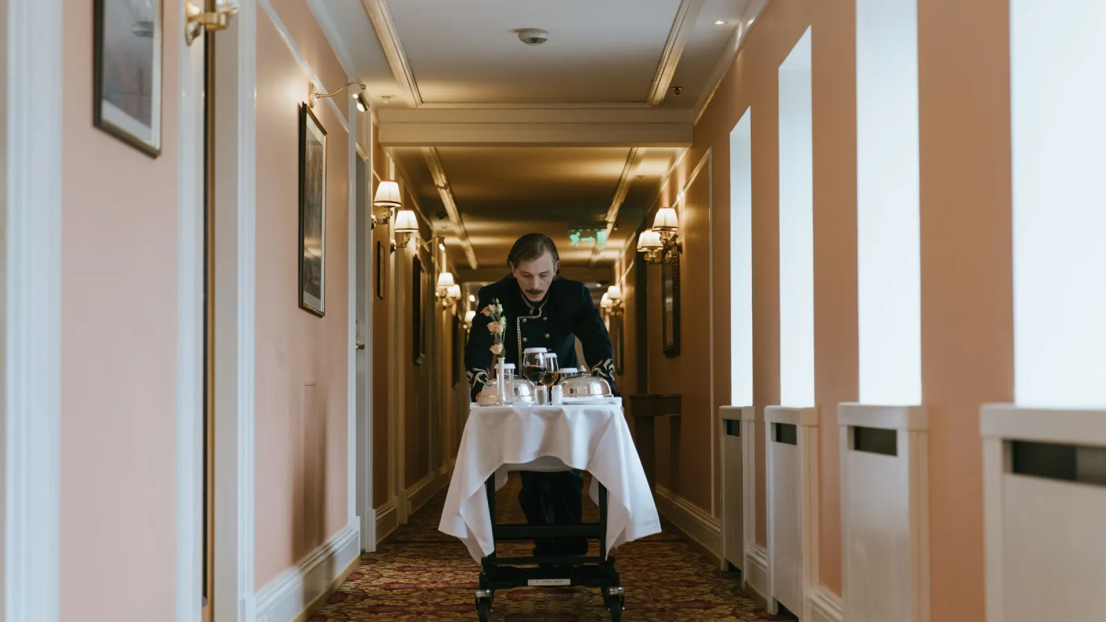 Hotel waiter pushing a room service trolley along a hotel corridor